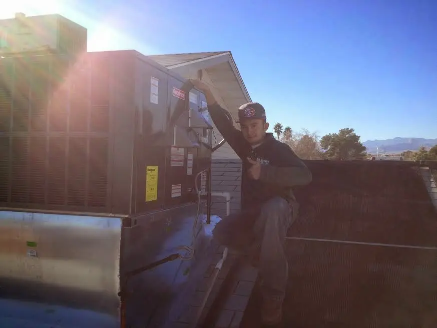 HVAC technician performing Air Duct Cleaning on a rooftop unit in Firestone