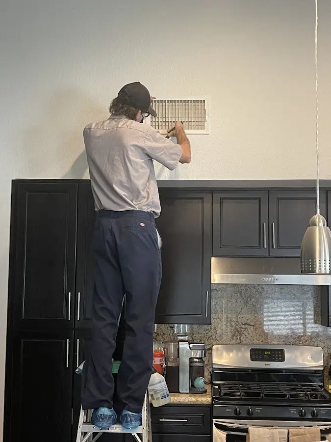 Technician inspecting an air vent during HVAC service in Firestone